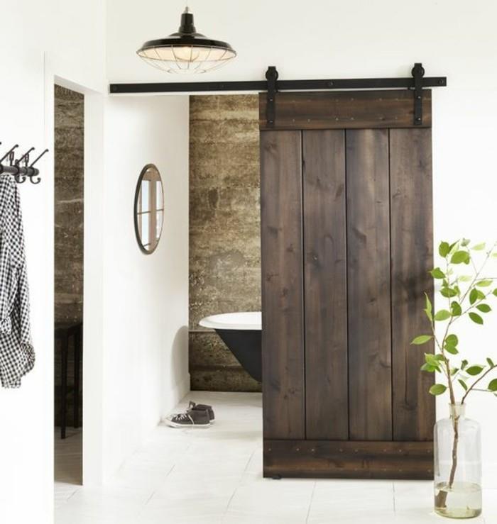 kaimiškas vonios kambarys su tamsiai medine tvarto durų vonia