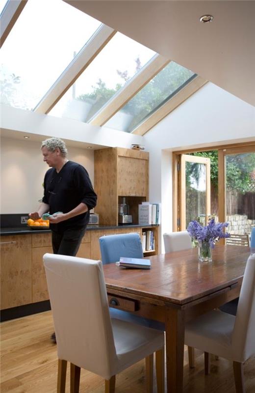 dnevna soba-s-kuhinjo-velika-lesena-miza-steklo-streha-streha-okno-velux