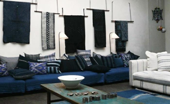 orientalska-dnevna-soba-bela-stenska-slika-dolga-indigo-modra-kavč-blazine-v-modro-sivo-črno-rabljena-kovina-mizica-in-orientalska-stenska dekoracija