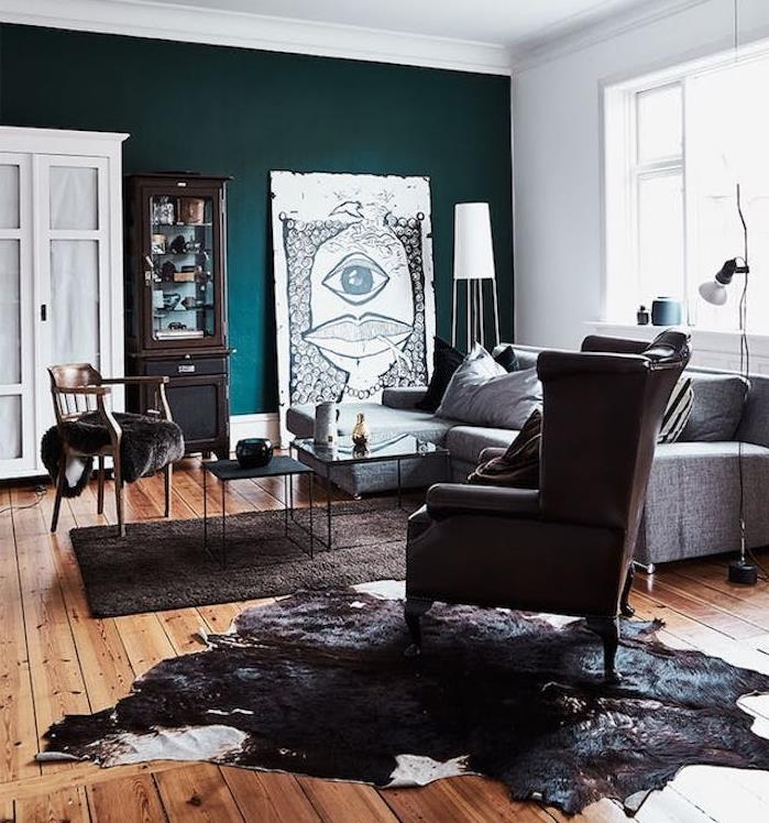 meniškas naftos mėlynos spalvos svetainės modelis, rudas parketas, sofa, fotelis ir pilkas kilimas, gyvūnų oda, fono siena, žalias atspalvis, neįprasta nespalvota dekoratyvinė plokštė, meniškas senovinis dekoras