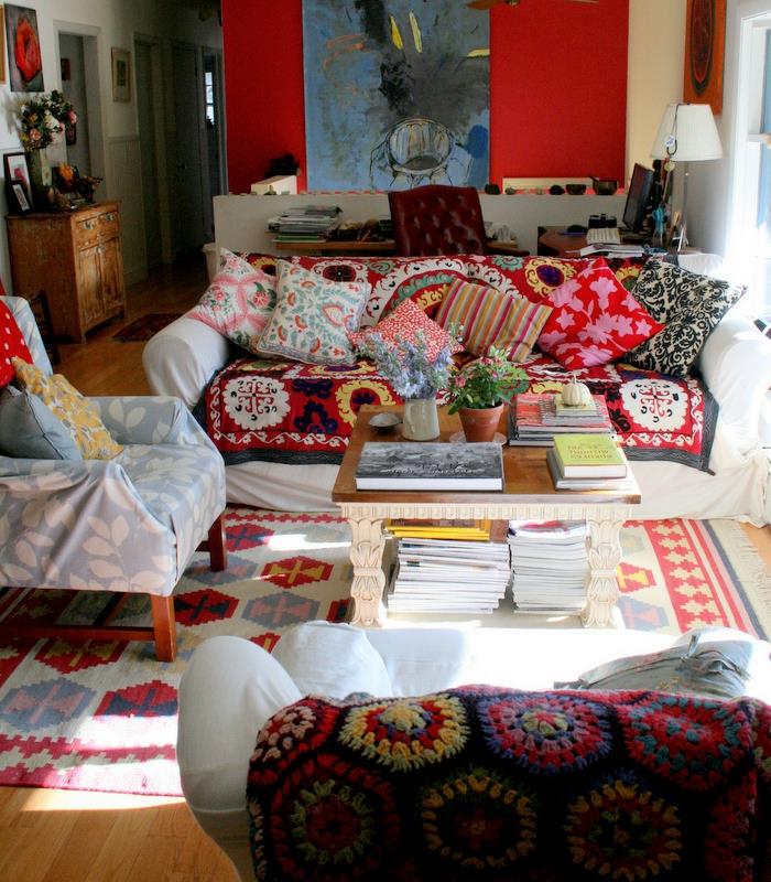 hipių kambarys, medinės grindys, raudona siena, etninio modelio pagalvėlės