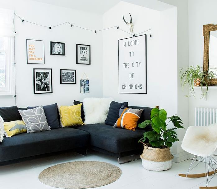 bela dnevna soba s črnim kavčem, bela talna obloga, okrogla preproga, skandinavski stol s krznenim metom, pisane okrasne blazine, črno -bela foto stena
