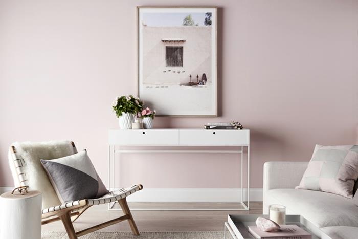 pilka ir rožinė svetainė, šviesiai rožinė siena, baltas konsolinis stalas, patogi kėdė, šviesiai pilka sofa