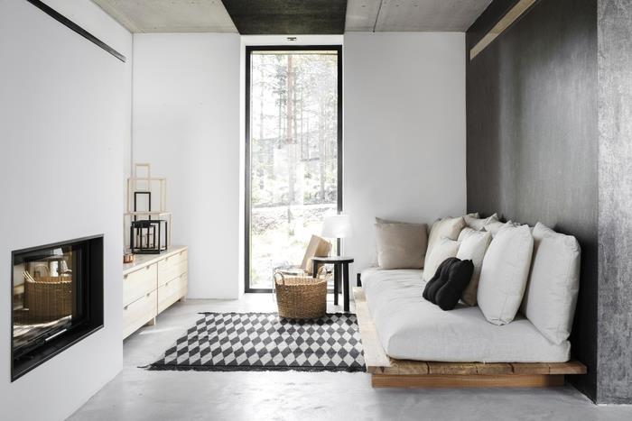 Şık tasarımlı bir palet kanepe ile donatılmış küçük, zarif siyah beyaz bir oturma odasının yerden tasarruf sağlayan düzeni