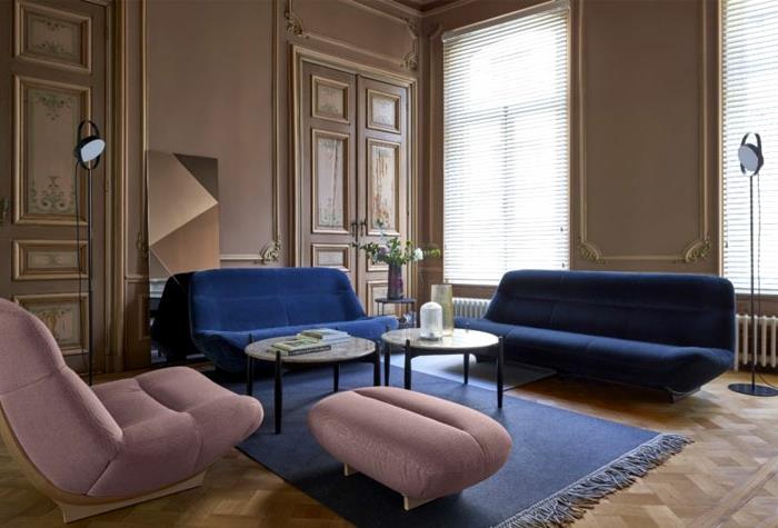 dnevna soba v modri in roza barvi, roza naslanjač in stolček, modre zofe, modra preproga, stene pobarvane s pepelom