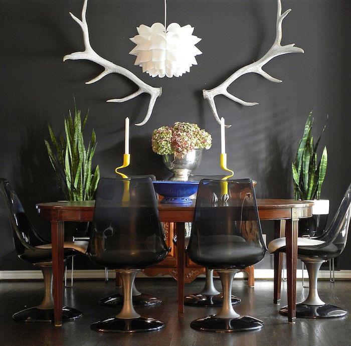 Dekor jedilnice z belimi jelenovimi rogovi, retro ovalno leseno mizo in starinskimi črnimi plastičnimi stoli