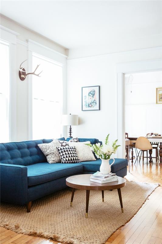 svetainė su neutraliais tonais ir skandinaviškais dekoratyviniais akcentais, sustiprintais povo mėlyna sofa