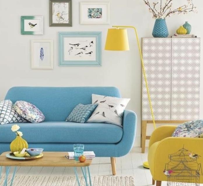 Mavi ve sarı İskandinav oturma odası dekoru, mavi kanepe, sarı koltuk, ahşap ve metal sehpa, kuş çizimleri çerçeveli duvar dekorasyonu, ahşap dolap, çiçek vazoları