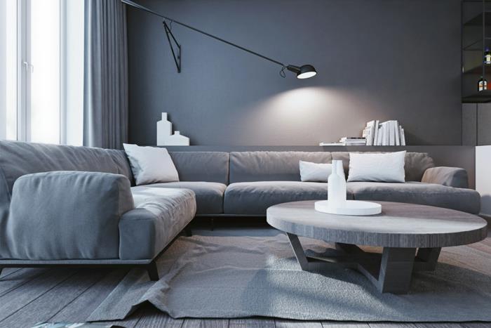 pilkas kilimas pilkoje svetainėje, patogi kampinė sofa ir apvalus svetainės stalas