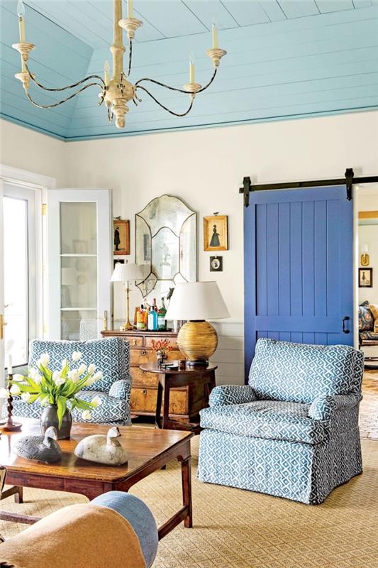 modro pobarvana drsna vrata s hlevom z ročajem in kontrastnimi črnimi tirnicami, ki se ujemajo s šarmantnim dekorjem podeželske elegantne dnevne sobe