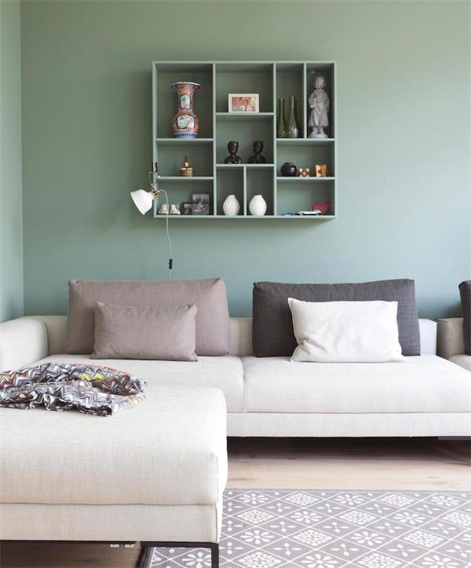 Celadon zelena postavitev dnevne sobe, sivo bel kotni kavč, sive blazine, siva in bela preproga, svetel parket in zelena odprta polica, shramba za budistične dekorativne dodatke