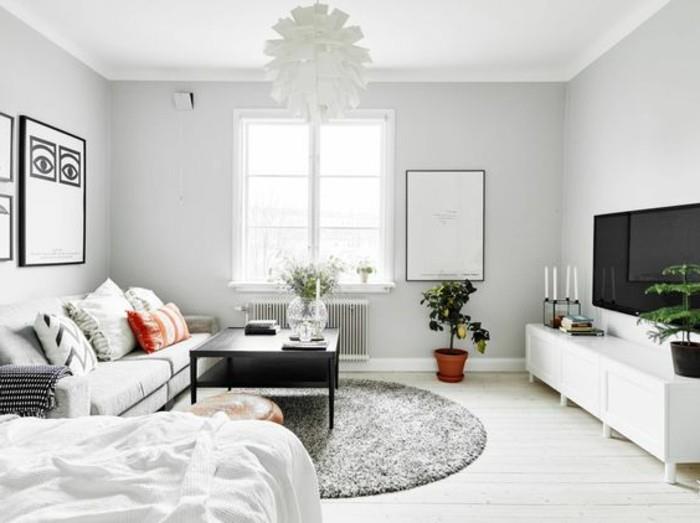 una zona living con a divano linear, a tavolino quadrato nero, the mobile tv bianco and a tappeto rotondo