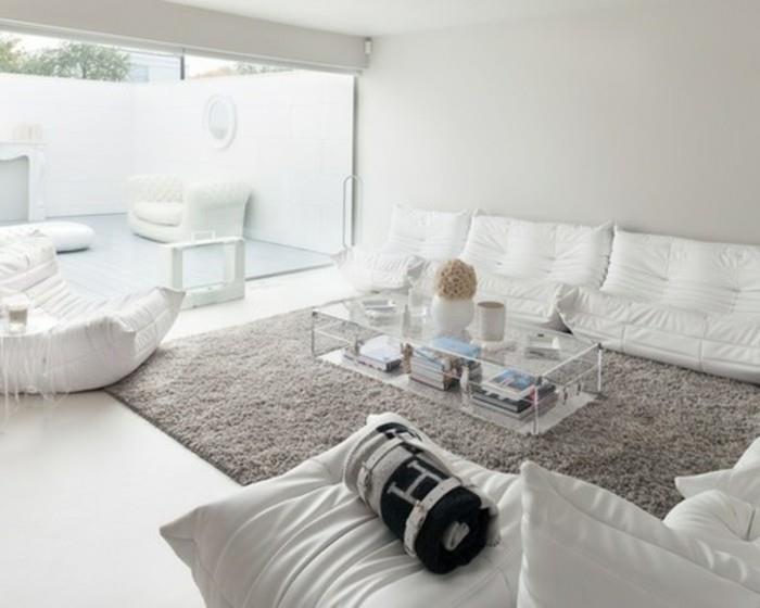 Mobili da soggiorno di colore bianco, divano in tessuto, tavolino basso di vetro