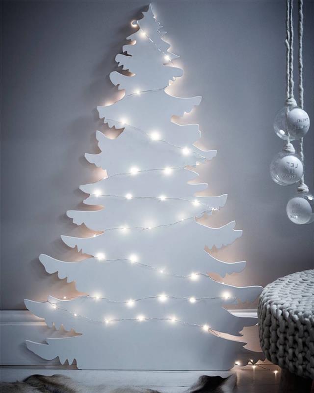 Romantik ve şiirsel Noel dekoru, tamamı beyaz, beyaz Noel ağacından bir tahtadan kesilmiş ve çelenkin küçük ışıklarıyla aydınlatılmış.