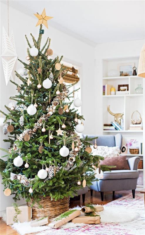 Božično drevo, okrašeno z hlodi, z zlatimi in belimi božičnimi kroglicami in borovimi storži v snežni efektu v beli dnevni sobi
