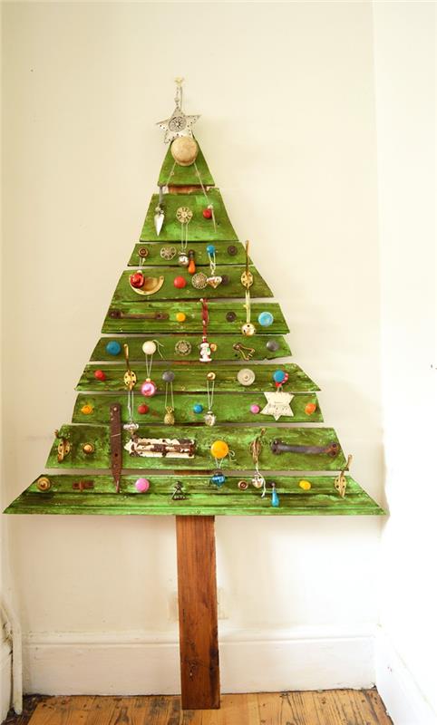 geri dönüştürülmüş bir paletten yapılmış ve küçük süslemelerden oluşan orijinal bir dekorasyonla yeşile boyanmış ahşap Noel ağacı