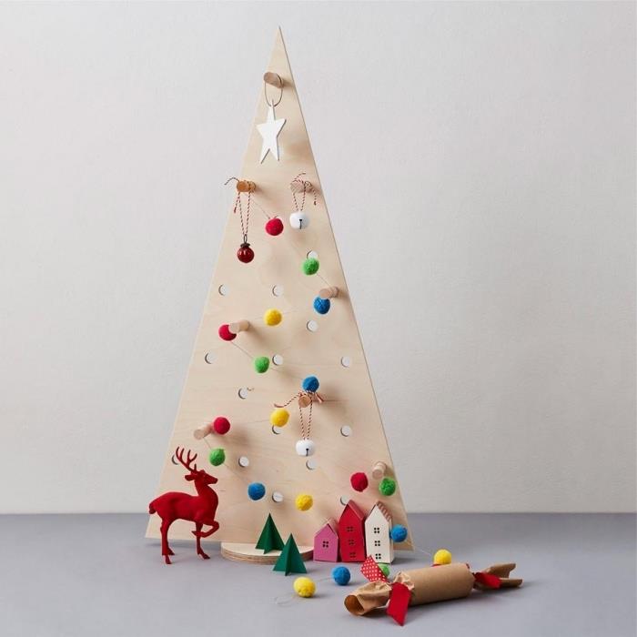 ahşap bir tahtadan kesilmiş, çok renkli yün ponponların süspansiyonlarıyla süslenmiş orijinal bir Noel ağacı