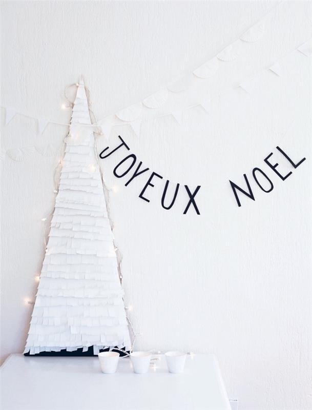 Küçük kağıt Noel ağacı, saçaklı beyaz kağıtla kaplanmış ve duvara yaslanmış masanın üzerine yerleştirilmiş bir karton tabandan yapılmıştır.