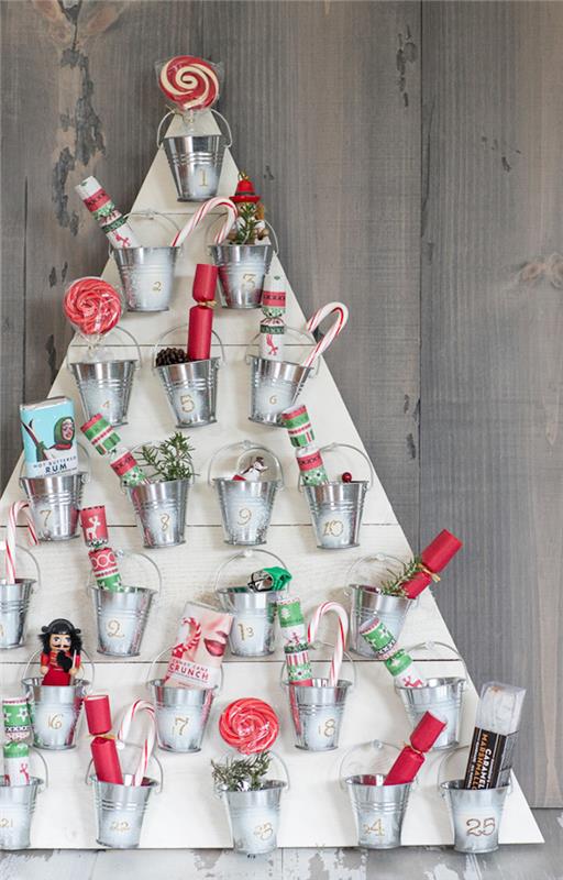 Kalėdų eglutės medinių lentų advento kalendorius su mažais dekoratyviniais kibirais, pripildytais mažų dovanėlių ir skanėstų
