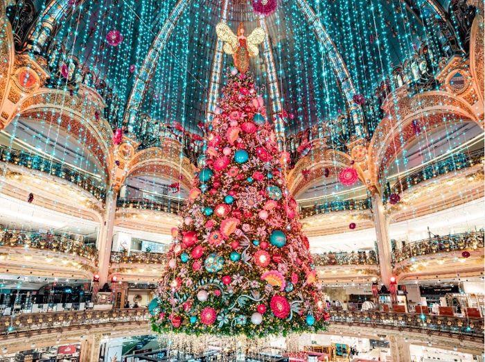 velikansko božično drevo, okrašeno z rožnatimi in modrimi božičnimi kroglicami ter okrasnim angelskim drevesom na vrhu, okrasnim dežjem luči s stropa