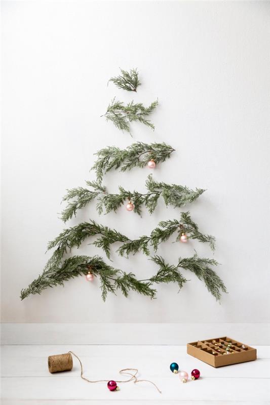 minimalist ve yerden tasarruf sağlayan Noel ağacı dekorasyon fikri, birkaç küçük Noel topuyla süslenmiş bir Noel ağacının şeklini oluşturmak için duvara yerleştirilmiş köknar dalları