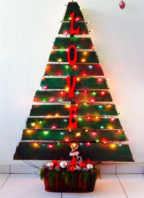 renkli ampuller, yığılmış Noel oyuncakları ve yeşillikler, büyük dekoratif harfler, palet ağacı ile sıcak Noel ağacı