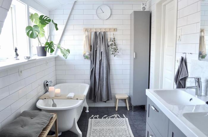 oblikujte manjšo mansardno kopalnico z belimi keramičnimi stenami in sivim podom z dvojno omarico in retro skandinavsko samostoječo kadjo