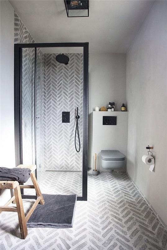 kopalnica iz voskanega betona s sivo cementno steno na tleh in italijansko prho s črno steno in majhno kmečko leseno klopjo