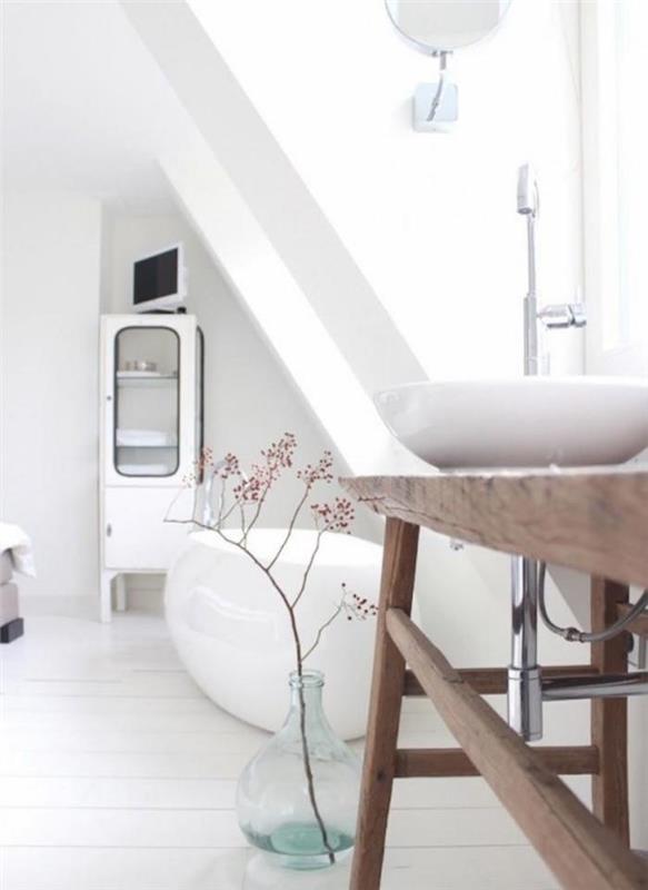 kopalnica s fotografijami, opremljena na podstrešju z udobnim modernim retro skandinavskim dekorjem z belo stensko kadjo in svetlečim oblikovalnim umivalnikom ter starinsko kmečko leseno umivalnico na belem parketu
