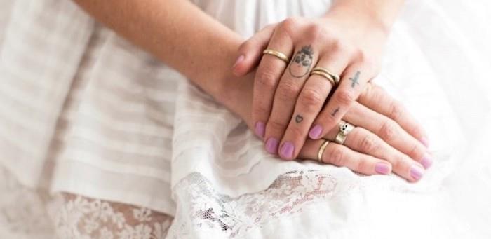 roke počivajo na beli obleki, križ srca in lobanje, tetovaže s prsti, tetovaža rožnih prstov, roza lak za nohte