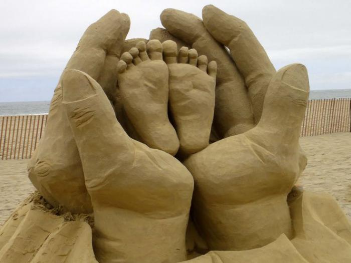 peščena skulptura rok, ki se držijo za noge