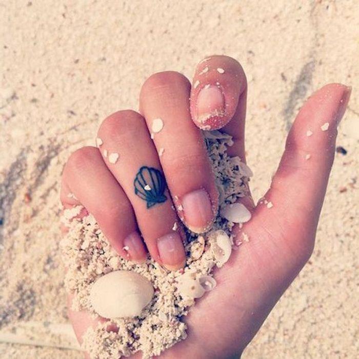 majhna školjka, tetovaža z prstanom, tetovaža z rožnatim prstom, roka, ki drži pesek na plaži, majhne školjke