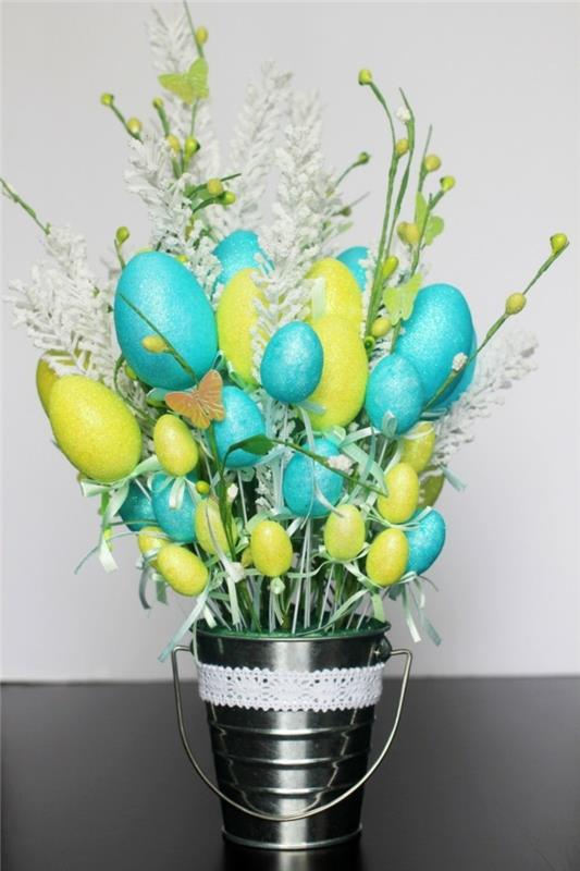 Gražiai sutvarkytas dekoratyvinis kibiras su gėlėmis ir Velykų deko kiaušiniais nuostabus