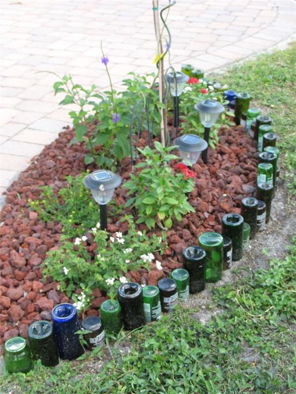majhen cvetlični skalnjak, obložen s steklenicami vina, postavljenimi na glavo, izvirna zamisel za dekoracijo vrta