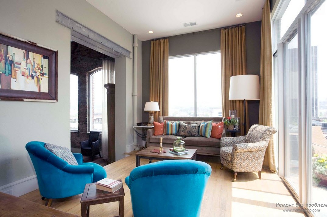 Dos sillones de color azul brillante diluyen el interior gris de la sala de estar