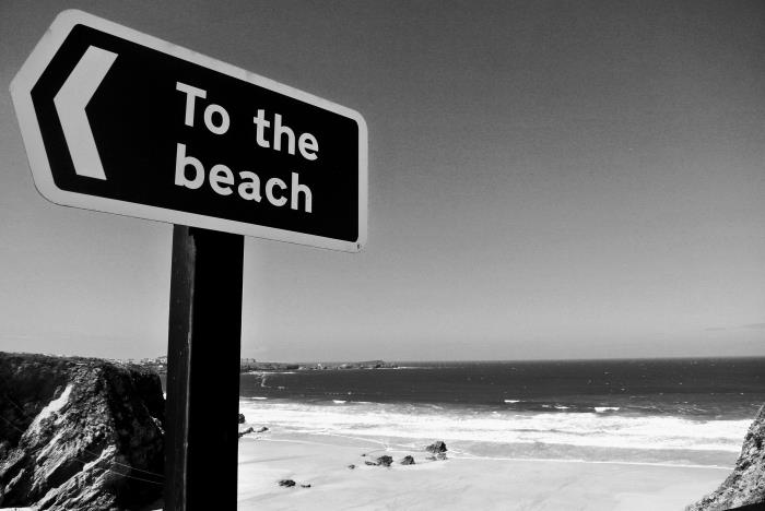črno -bela fotografija smernega znaka in zapuščene plaže v ozadju, enobarvna fotografija