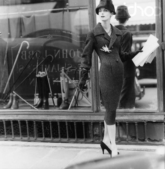 Silhueta peščenih ur, črni čevlji s peto, izviren klobuk, ženska, ki drži papir v rokah