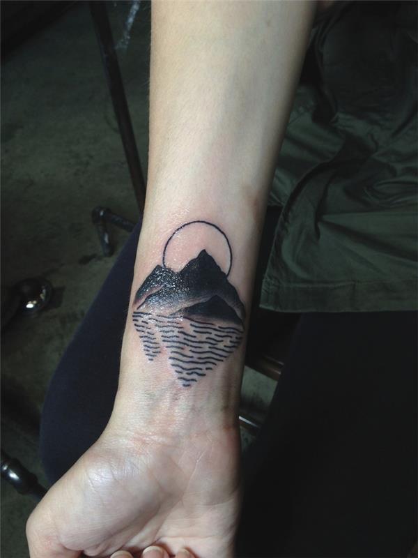 „Simboli geometrici and unideide per tatuaggio sul polso di una montagna che si riflette sul mare“