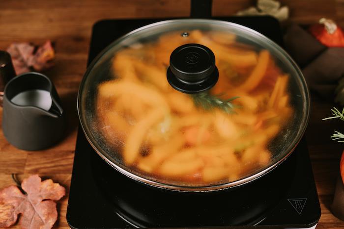 juoda keptuvė, uždengta dangčiu, bulvių sriubos receptas, pieno ąsotis šone, medinis stalas su rudeniniais lapais