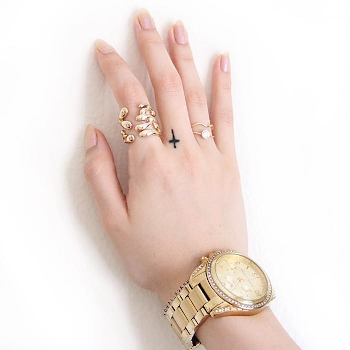 velika zlata ura, majhen križ, tetovaža s srednjim prstom, par tetovaž s prsti, zlati prstani