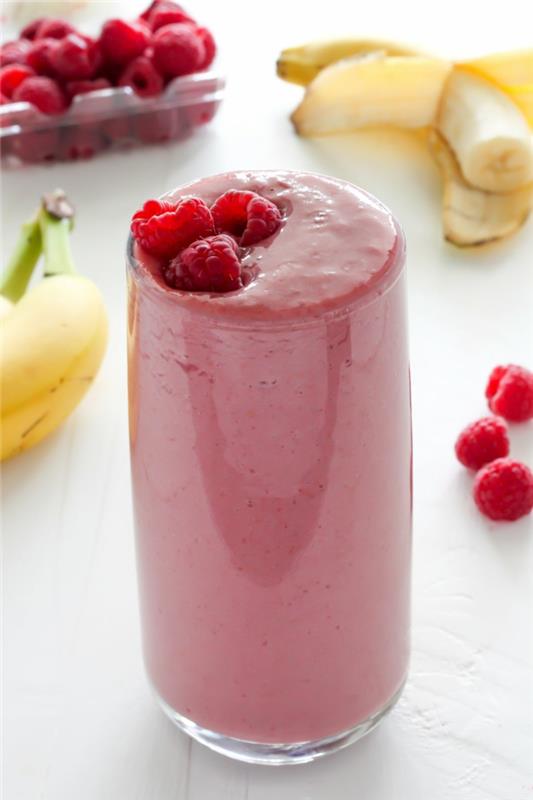 skodelica polna roza smoothieja z malinami in bananami, poživljajoča pijača