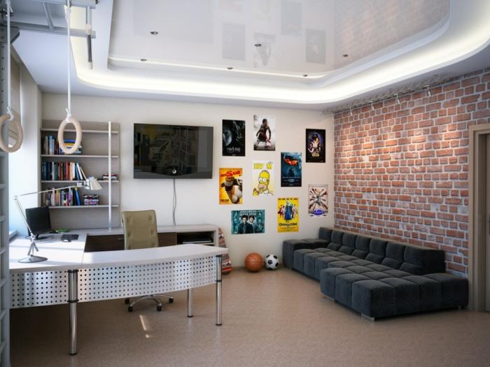 industrinio stiliaus paauglių berniuko kambarys, žema juoda sofa, plytų siena, U formos stalas, sieniniai plakatai ir gimnastikos žiedai