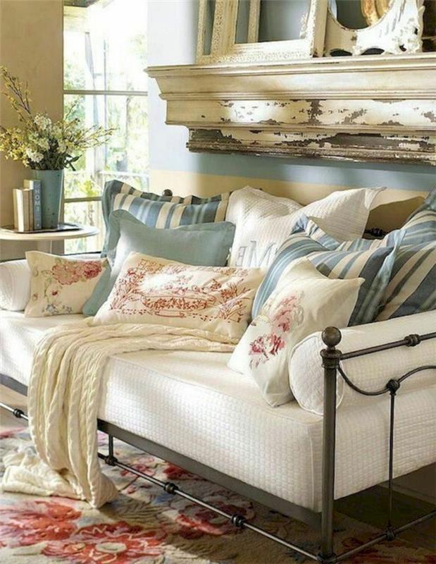 beli kavč, perzijska preproga, črtaste blazine, pletena pletenina v krem ​​barvi, modra stena, vaze, zastareli okvirji