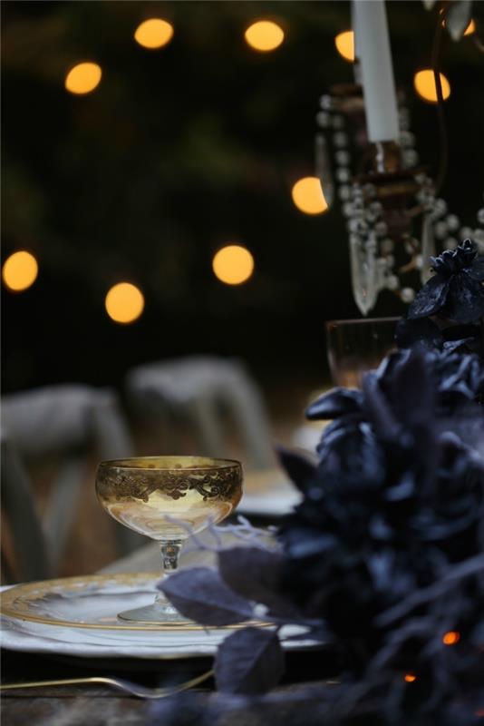 cadılar bayramı masası dekorasyon fikri, siyah kuru yapraklarla süslenmiş yemek masasının üstündeki hafif çelenk