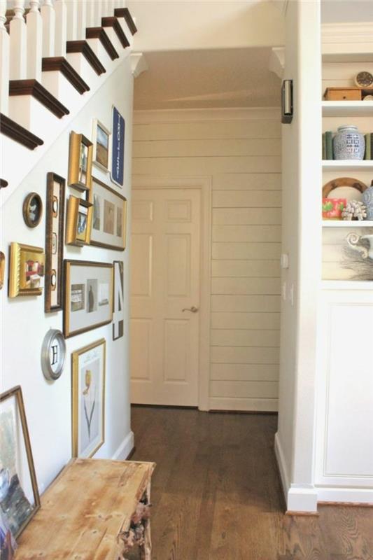 veliko okvirjev različnih oblik in velikosti, na beli steni pod stopniščem, ideje za okrasitev hodnika, tla iz masivnega lesa, bele police z različnimi predmeti