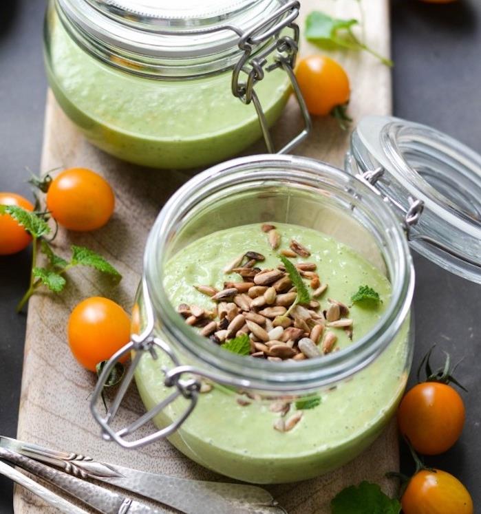 šaltos agurkų ir avokadų sriubos idėja su saulėgrąžomis ant viršaus stikliniame inde, gurmaniško šalto užkandžio receptas