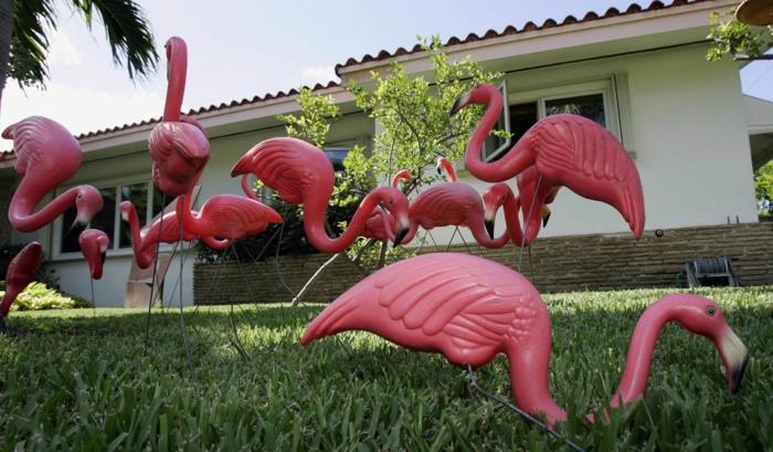 flamingo deco, kip flaminga, tropski deco, vzorec tropskega listja, zelena trava na vrtu in rožnate plastične figure flaminga