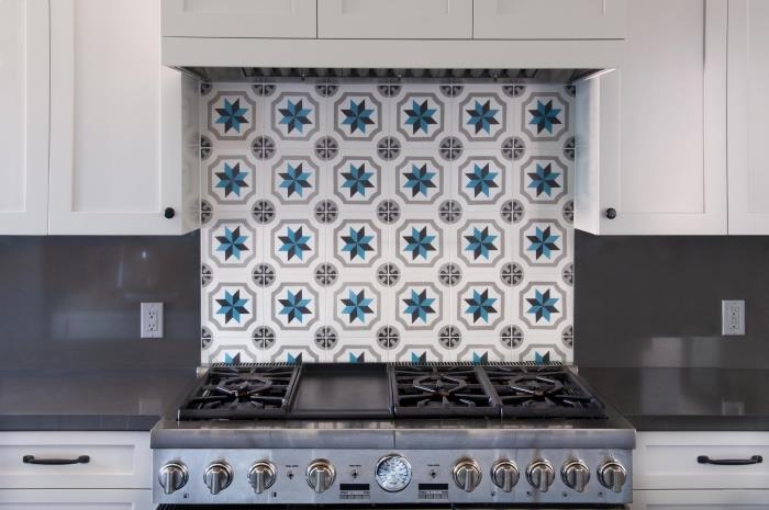 cementne ploščice backsplash v beli in modri barvi, belo kuhinjsko pohištvo z antracitno sivimi pulti