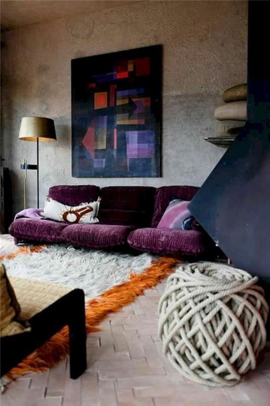 prostorna dnevna soba, otoman v grobi volneni niti, abstraktna slika na steni, talna svetilka, vijolična zofa