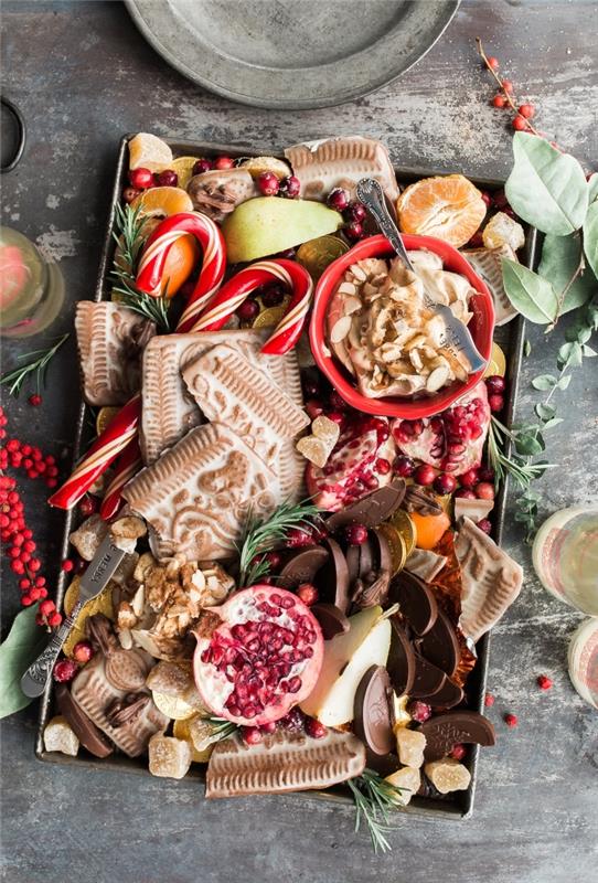 Ideja ameriškega recepta za božične piškote, božični pladenj s sadjem in domači piškoti, okrašeni z vejami jelke in suhim sadjem